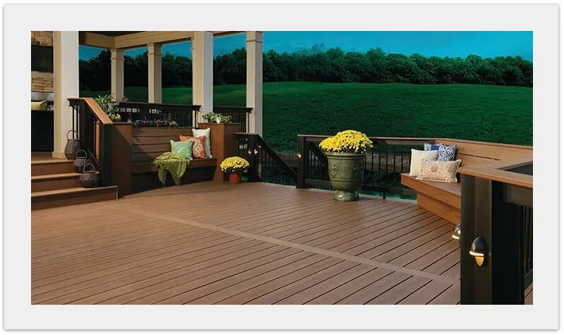 Low composite deck with wide steps, built-in bench, black aluminum railing, and potted flowers