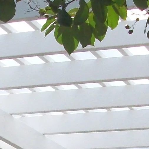 White vinyl pergola with a slatted roof and sunlight filtering through the beams